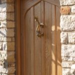 Closer view of arched door in oak with a beautiful dolphin knocker