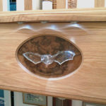 carving of bat set in cocobola veneer panel set in oak with lights